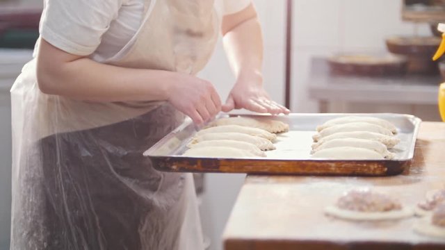 Cook puts pies on the tray for baking