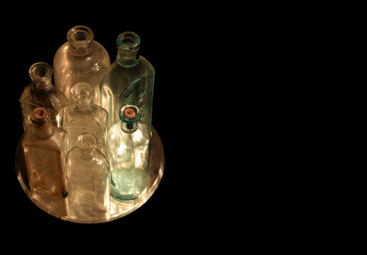 Dust on the Bottle, a tight group of old glass bottles isolated on black with copy space on the right.