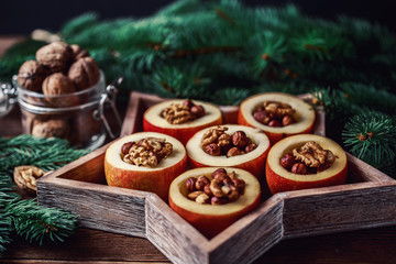 Baked apples with cinnamon on rustic background. Autumn or winter dessert. Closeup photo of a tasty baked apples with christmas decoration