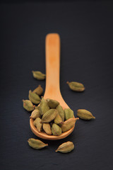 Healthy Food concept Aroma Spice dried Cardamoms in wood spoon on black slate background with copy for text