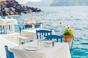 Greece, Santorini. Restaurant with served table in seafront of Aegean sea on Santorini Cyclades...