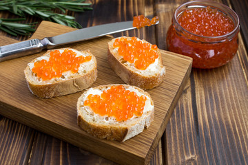Sandwiches with red caviar on the wooden cutting board
