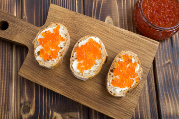 Sandwiches with  red caviar on the wooden cutting board.View from above.