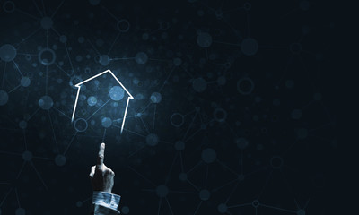 Conceptual image with hand pointing at house or main page icon on dark background