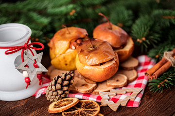 Obraz na płótnie Canvas Baked apples with cinnamon on rustic background. Autumn or winter dessert. Closeup photo of a tasty baked apples with christmas decoration