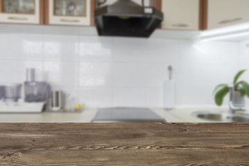 Wooden textured table over blurred kitchen interior background