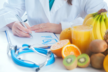 Female dietician writing a diet list with fresh season fruit