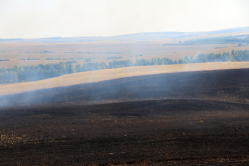 Burnt out smoking steppe after disastrous fire