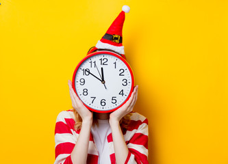 Woman hiding with big clock on on yellow background