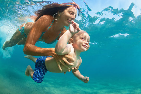 Happy family - mother with baby son dive underwater with fun in sea pool. Healthy lifestyle, active parent, people water sport outdoor adventure, swimming lessons on beach summer holidays with child