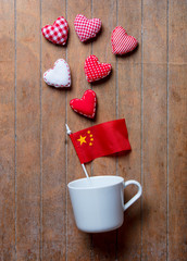 White cup on lying on side with China flag and heart shapes
