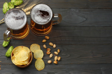 Glass beer with hop cones, pistachio and wheat ears on dark wooden background. Beer brewery concept. Beer background. top view with copy space