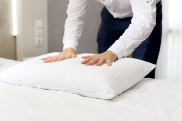 Obraz na płótnie Canvas hotel staff setting up pillow on bed