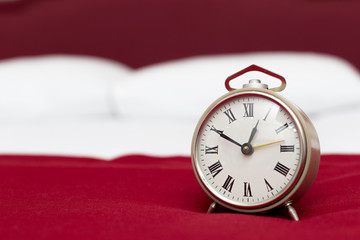 Vintage alarm clock on a bed in a hotel room. Wake up call concept