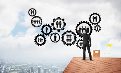 Businessman on house roof presenting teamwork and connection concept. Mixed media
