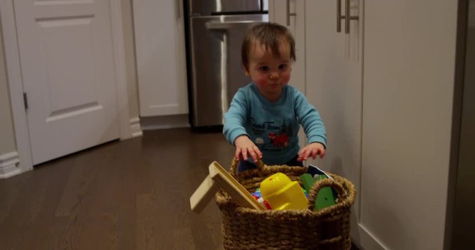 Baby boy hobbles towards basket of toys - new to walking