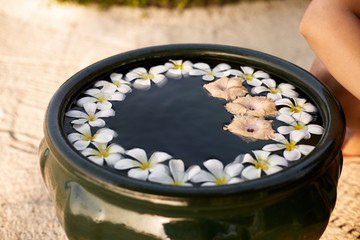 Woman makes decor arrangement in green bowl on the water of frangipani plumeria flowers. Isolated view of hands and floristic composition. Aroma spa concept.
