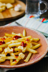 Poutine fries on black surface. Canadian dish with potatoes, cheese and sauce.