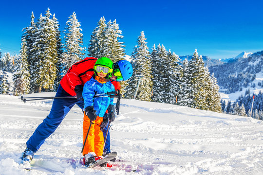 Happy little boy having fun with his father on ski holiday in Alps