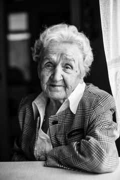 Portrait of an elderly woman sitting at the table, a black-and-white photo.
