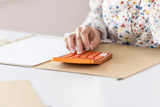 Woman calculating on orange desktop calculator