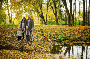 Fototapeta premium Happy caucasian family of mom dad and little girl with boy at majestic autumn fall forest.