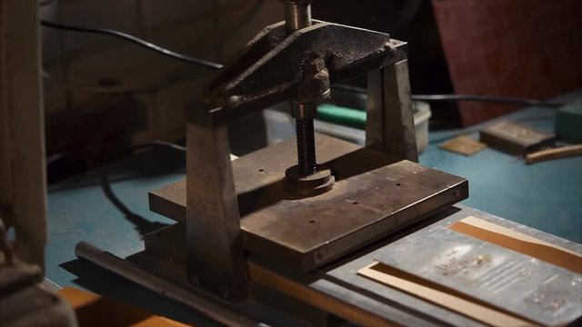 Worker making a stamp on leather using embossing press machine