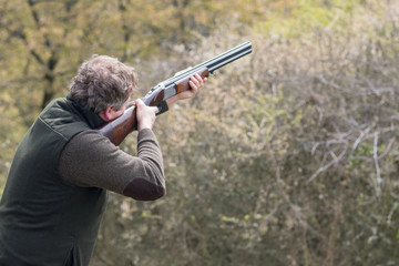 Hunter in forest during hunting season aiming before shoot
