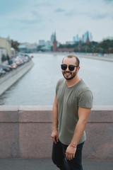 Happy hipster man on the Moscow city background. Russia, Moscow, Moskva river - 2016.