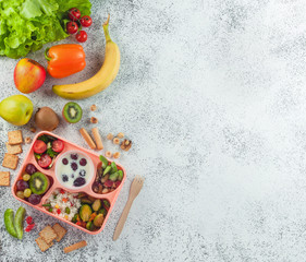 Lunch box with vegetable salad, berries in yogurt, fruits and rice on grey background
