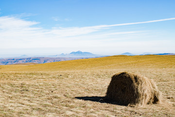 Haystack in autumn field, mountains