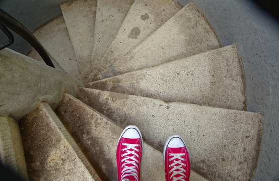 Rote Sneaker auf Wendeltreppe beim Abw&auml;rtsgehen