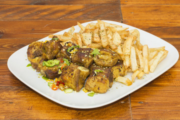 Un plato con costilla de cerdo asada y patatas fritas sobre una mesa de madera rustica