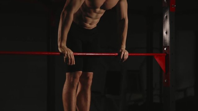 Sports inflated male performs a chin-up lifting above the horizontal bar. Power outlet.