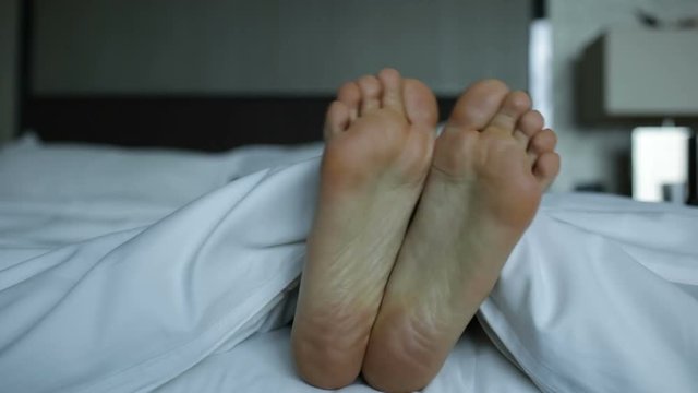 Happy dancing feet of a female in a bed
