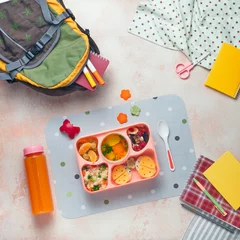 Fotobehang Open lunch box with vegetable soup, couscous salad and funny sandwiches near backpack and orange juice © lithiumphoto