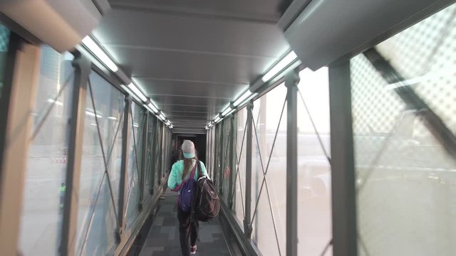 Girl going through corridor for boarding a plane.Departing passengers at the airport go through the landing gate on the plane. Holiday and travel concept.