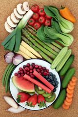 Health food for healthy eating concept with fresh vegetables and fruit on cork background, high in antioxidants, anthocyanins, minerals, vitamins and dietary fibre. Top view.