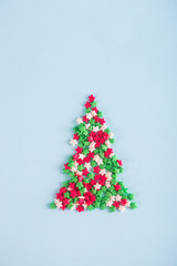Figure of fir tree consisting of colorful Christmas sprinkles in form of stars on light background