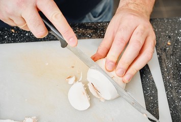 Cuoco taglia dei funghi sul tagliere