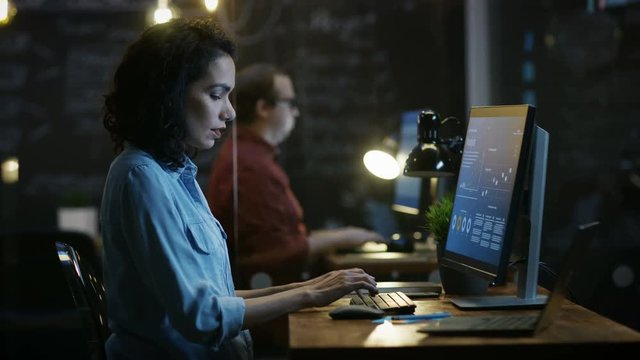 Stressed, Overworked Female Financier Holds Her Head in Hands while Working on a Personal Computer. In the Background Creative Office. RED EPIC-W 8K Camera.