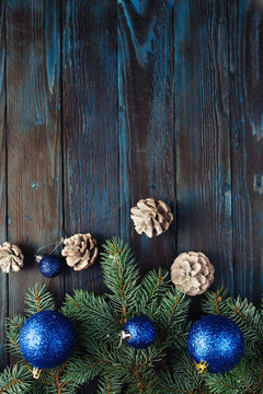 New Year and Christmas decorations Pine tree branches, cones, blue Christmas toys on a wooden background.