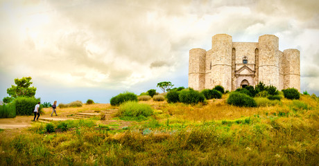 couple climb steps in a natural yellow landscape to reach  Castel del Monte in Apulia - Andria Trani province - Italy - obrazy, fototapety, plakaty