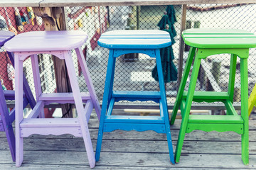 Colorful vivid chairs painted purple, blue and green on waterfront bar restaurant