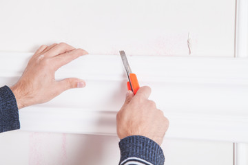 Man with knife cutting ceiling skirting.
