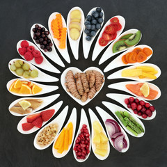 Health food nutrition for a healthy heart with fruit, vegetables, fish, herbs and spices with turmeric spice super food at the centre. Foods high in omega 3, antioxidants, fibre and vitamins. 