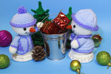 between two toy snowmen a bucket with gifts among the Christmas toys