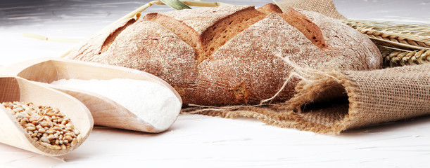 bakery concept with bread, flour and wheat on burlap