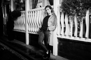 Girl with dreadlocks walking at night street of city.