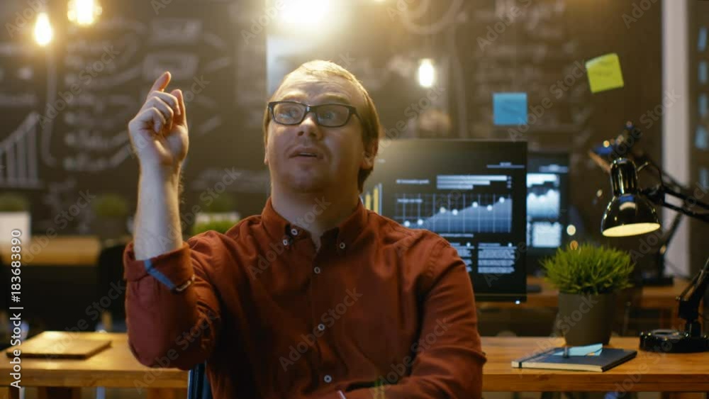 Poster young office worker has eureka moment while sitting in his office thinking, bulb over him lights up 